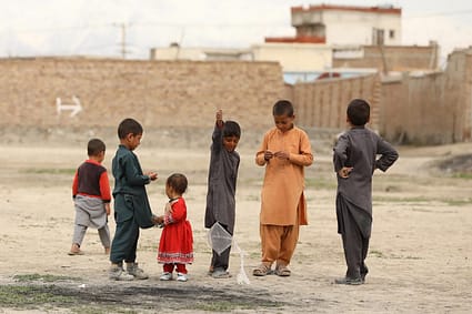 children in red and gray shirts standing on gray sand during daytime