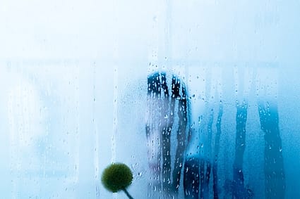 a person holding a flower in front of a window